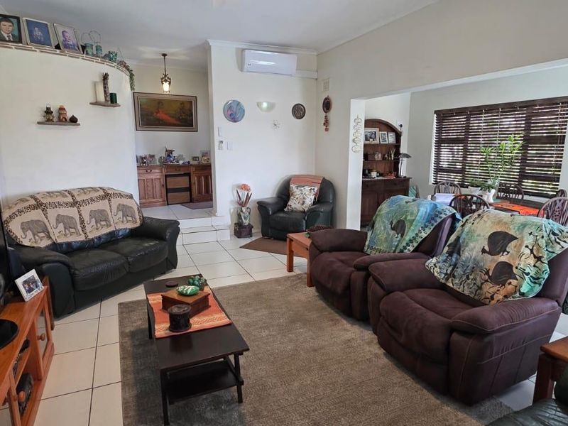 Open-plan living and dining area featuring tiled flooring, split-system air conditioning, and large windows with venetian blinds.