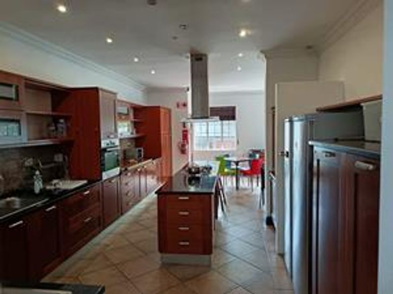 Spacious kitchen featuring dark wood cabinetry, a central island with granite countertops, built-in oven, and stainless steel extractor fan.