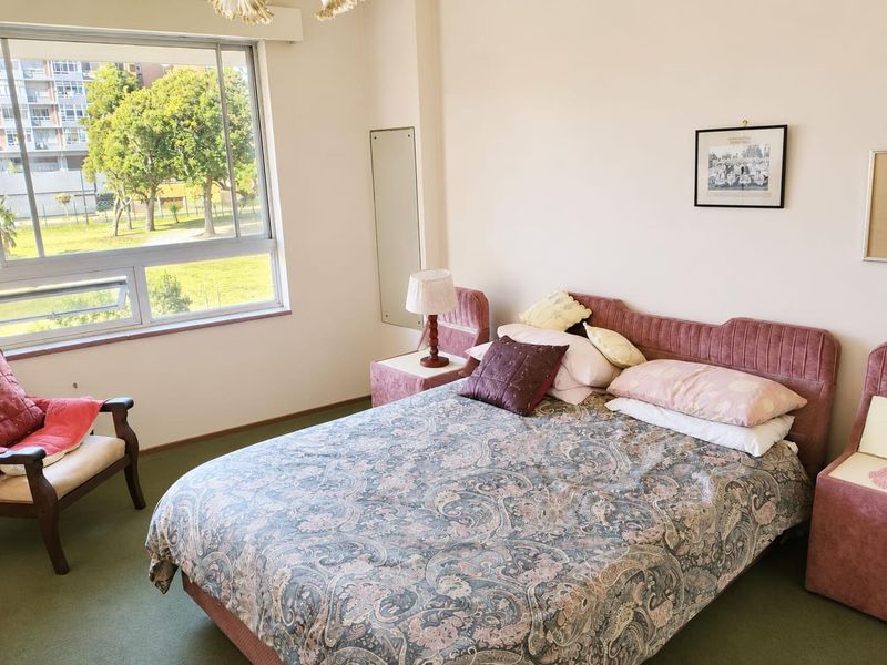 A bedroom featuring carpeted flooring and a large window providing natural light and views of the surrounding area.
