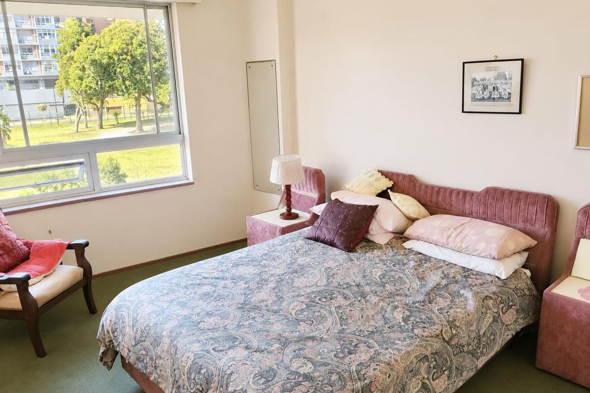 A bedroom featuring carpeted flooring and a large window providing natural light and views of the surrounding area.