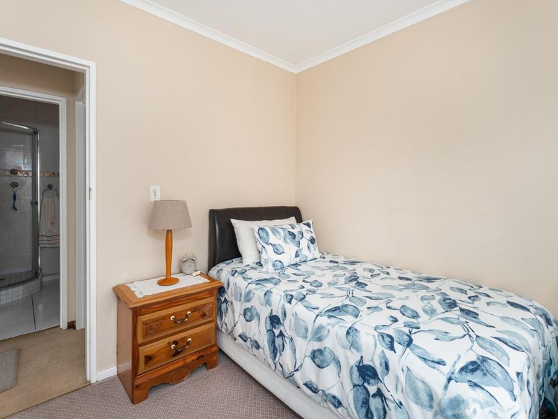A functional bedroom featuring neutral wall tones, carpeted flooring, and direct access to an adjoining bathroom.