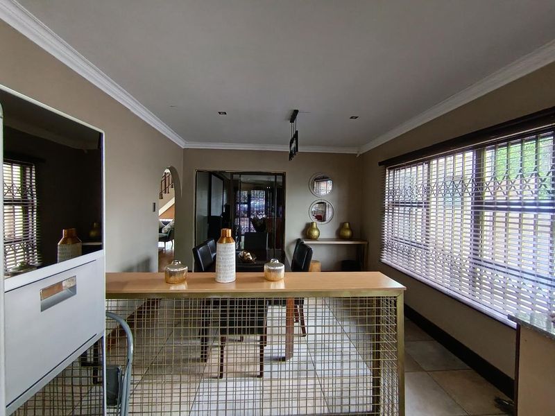 Open plan living and dining area featuring tiled floors, crown molding, recessed lighting, and a decorative metal room divider.