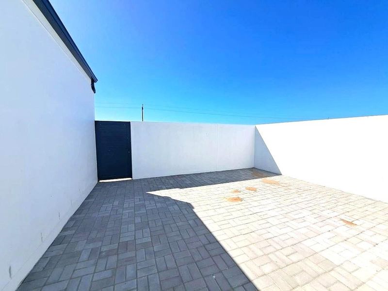 A private, paved rear courtyard enclosed by high boundary walls, featuring a secure pedestrian gate and clear outdoor space.