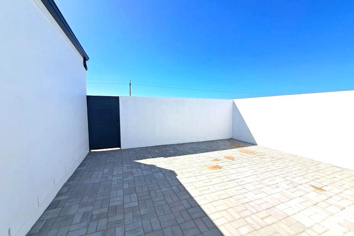 A private, paved rear courtyard enclosed by high boundary walls, featuring a secure pedestrian gate and clear outdoor space.