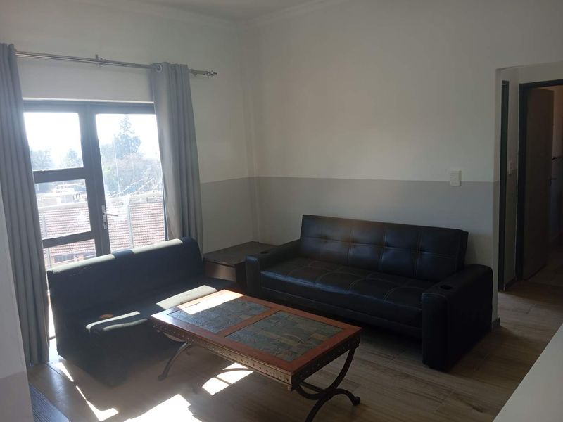 A living room area featuring tiled flooring, neutral wall paint, and a large window providing natural light.