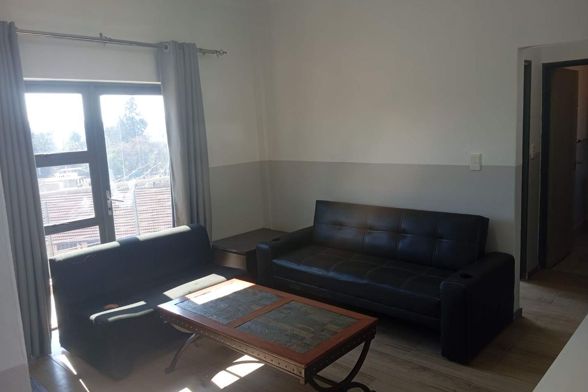 A living room area featuring tiled flooring, neutral wall paint, and a large window providing natural light.