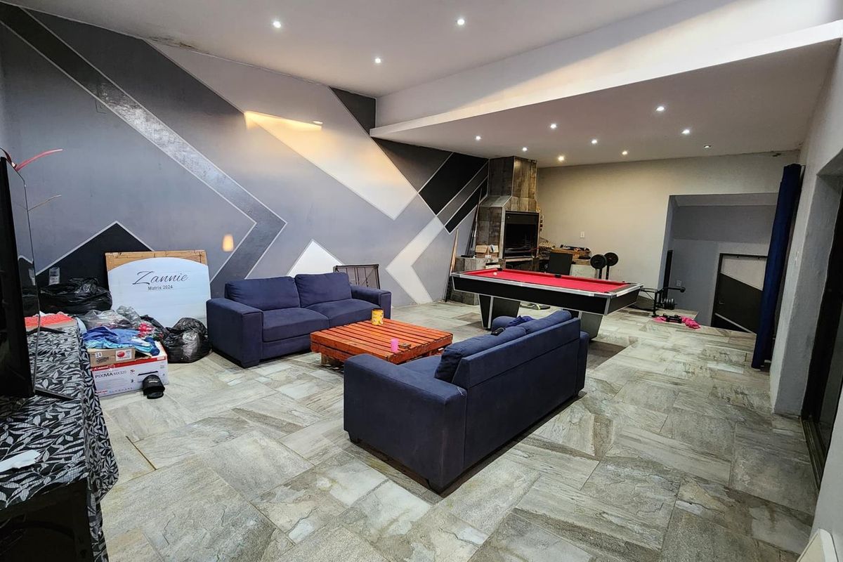 Spacious living area featuring large format stone floor tiles, recessed downlighting, and a built-in indoor fireplace.