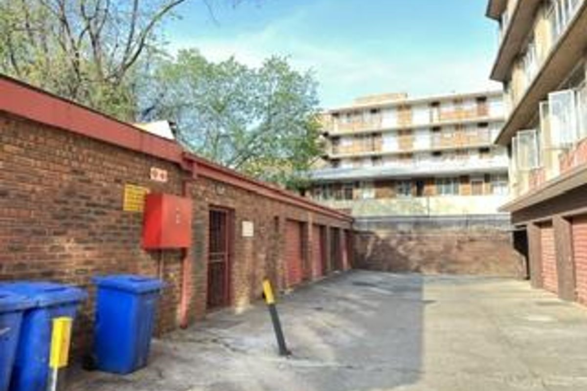 Rear exterior area of the apartment complex featuring brick walls, concrete paving, and secure access points.