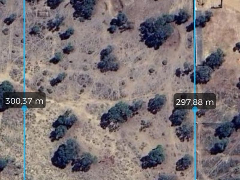 Aerial view of a vacant agricultural land plot showing boundary measurements and natural vegetation cover.