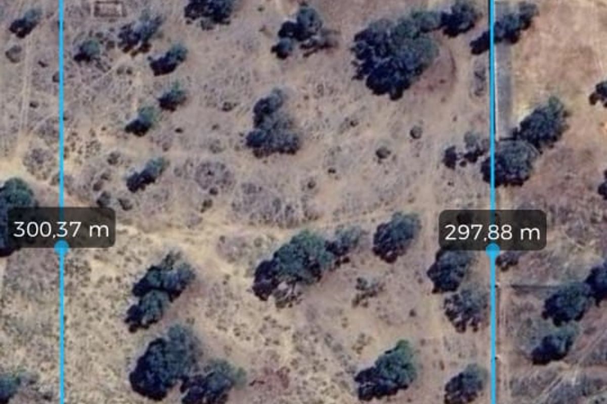 Aerial view of a vacant agricultural land plot showing boundary measurements and natural vegetation cover.