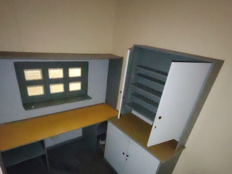 A small office space featuring built-in desk and storage cabinetry, requiring cosmetic updates to improve the overall condition and appeal.