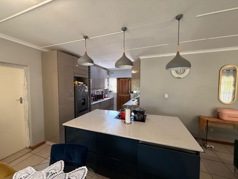 Modern kitchen featuring a central island with stone countertops, sleek cabinetry, and contemporary pendant lighting, providing a functional and stylish cooking space.