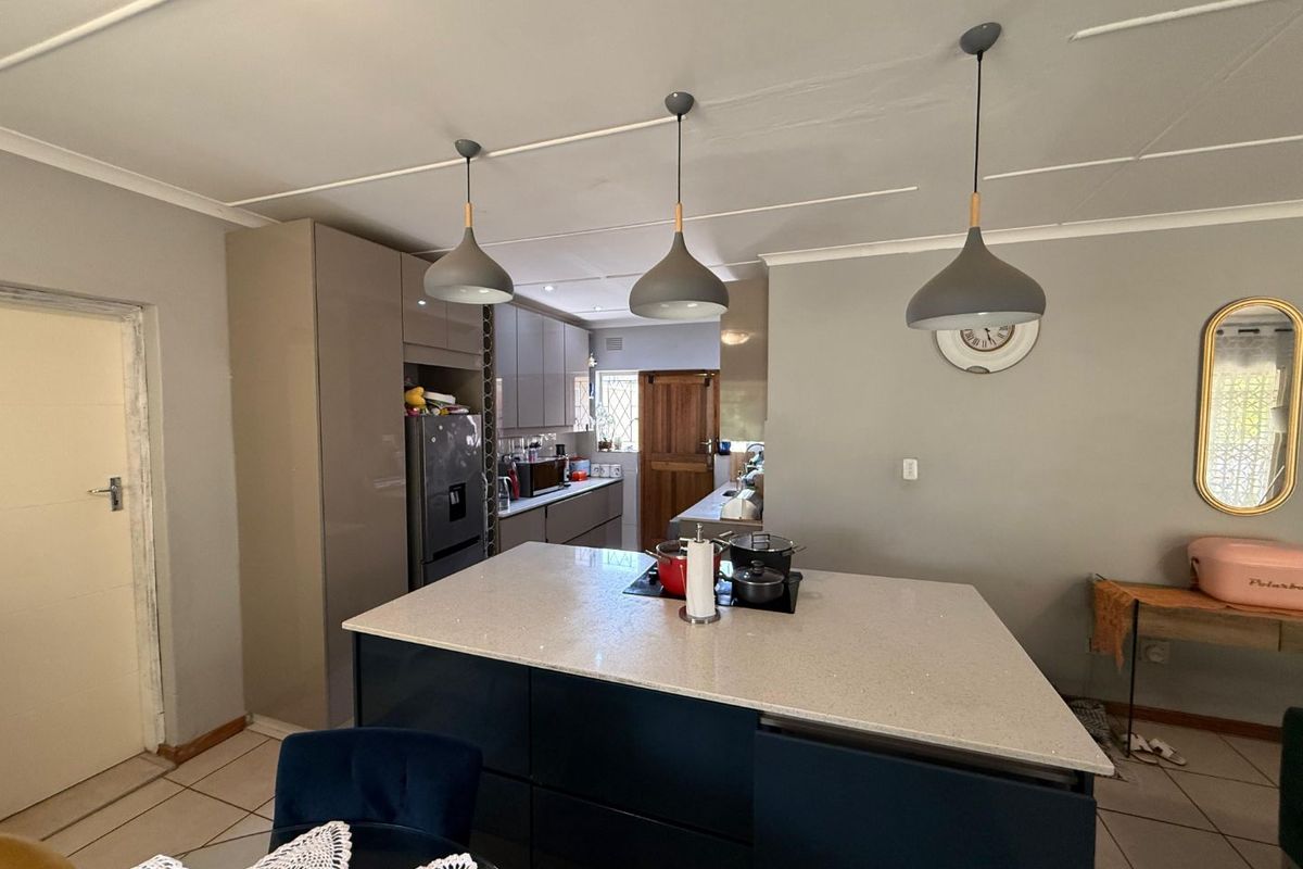 Modern kitchen featuring a central island with stone countertops, sleek cabinetry, and contemporary pendant lighting, providing a functional and stylish cooking space.