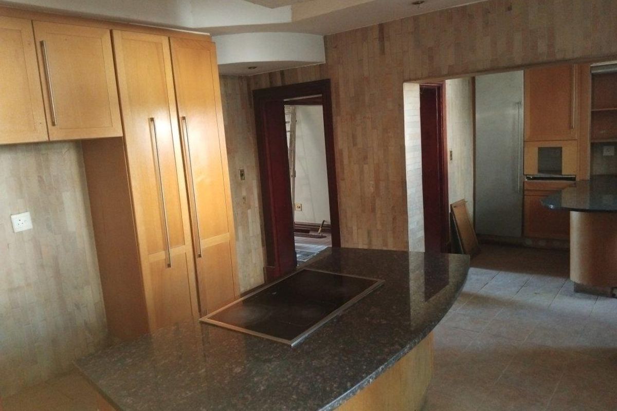 Spacious kitchen featuring a large granite island with integrated hob, extensive built-in cabinetry, and stone wall cladding, offering a functional layout for renovation.