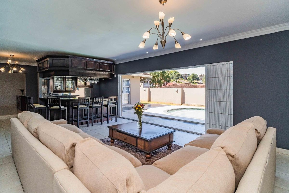Spacious living room featuring a built-in bar and large sliding doors that open directly to the outdoor pool area.