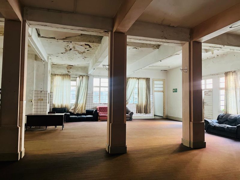 Spacious open-plan area featuring exposed concrete structural columns and beams, requiring significant renovation and ceiling repairs to restore the interior finishes.