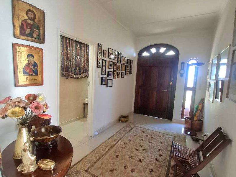 Welcoming entrance hall featuring tiled flooring, a solid timber front door with an arched transom window, and natural light from a side window.