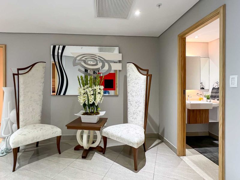 A well-maintained hallway featuring tiled flooring, recessed ceiling lighting, and a doorway leading into a modern bathroom.