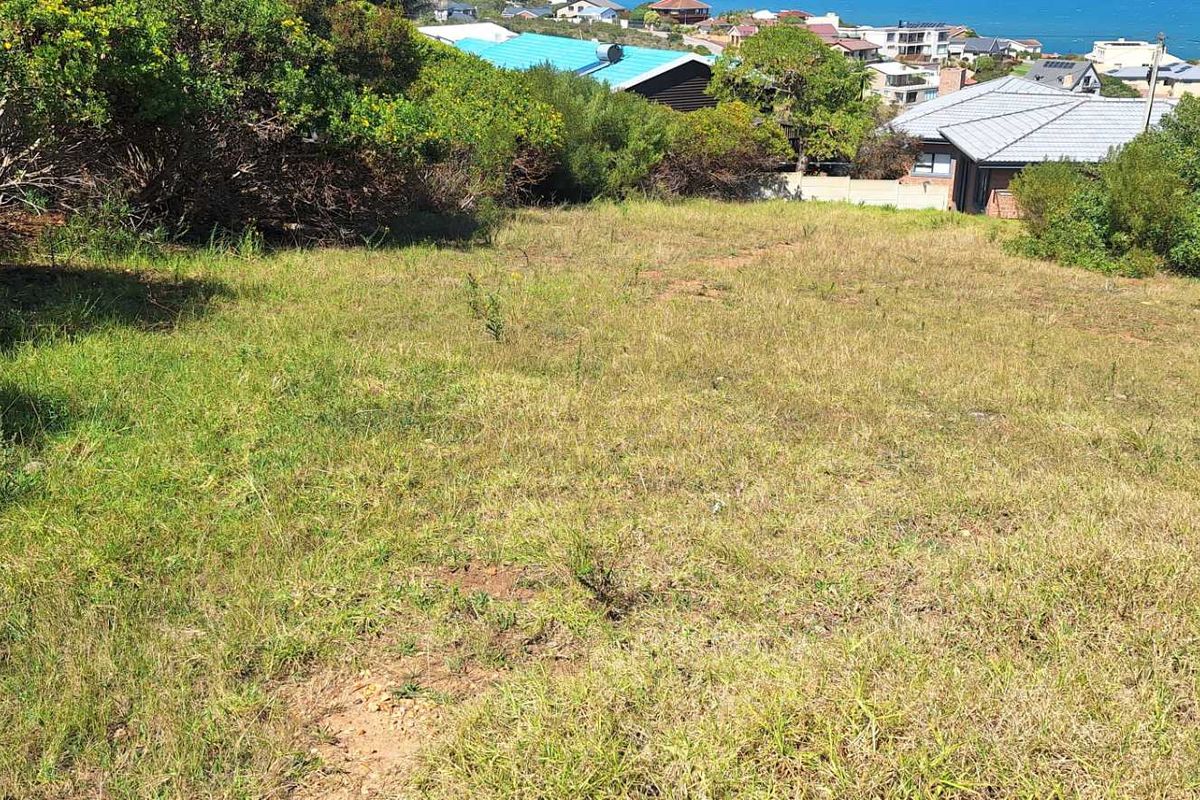 A sloped, undeveloped residential plot featuring natural vegetation and coastal views, offering a prime opportunity for custom home construction.