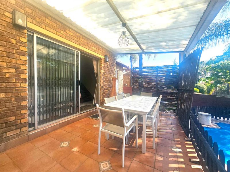 Covered outdoor patio area featuring tiled flooring, brick wall finish, and direct access to the interior through a sliding glass door.