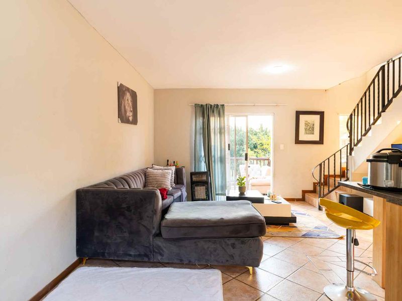 Open plan living area featuring tiled flooring, a staircase with a metal balustrade, and sliding glass doors leading to an outdoor space.