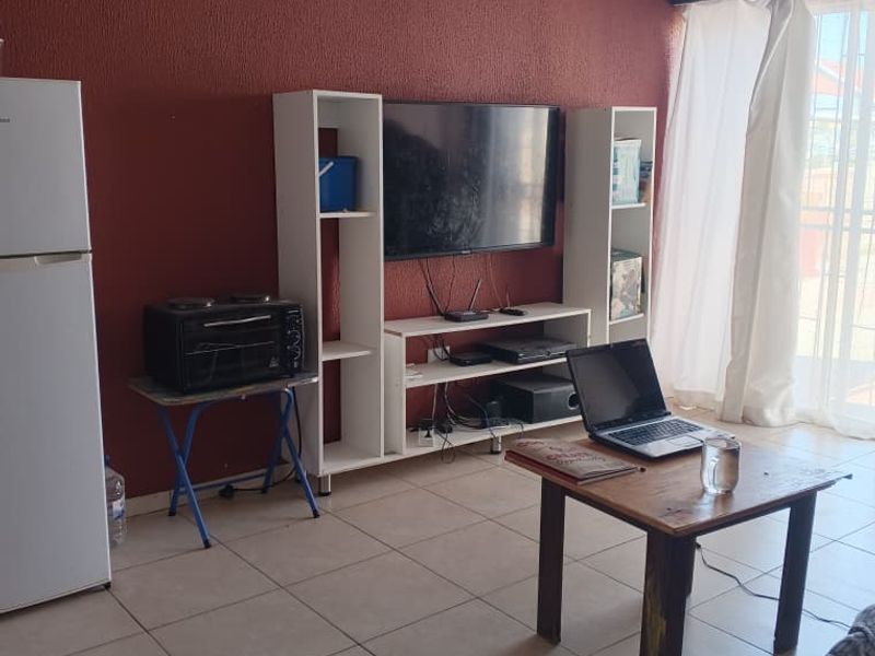 A living room area featuring tiled flooring, decorative ceiling cornicing, and a sliding glass door providing access to the exterior.