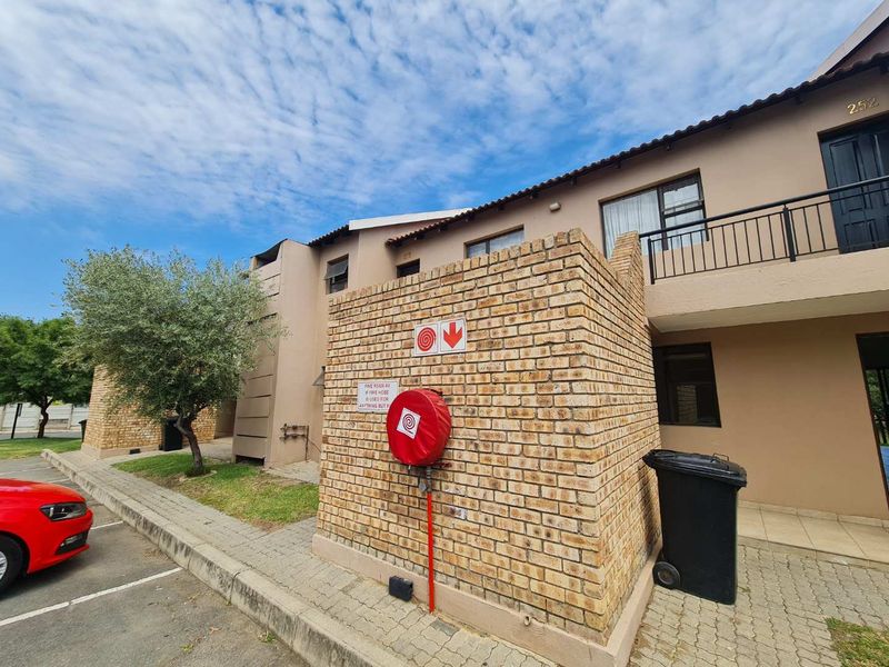 Exterior view of an apartment complex featuring a face brick facade, fire safety equipment, and paved driveway access.
