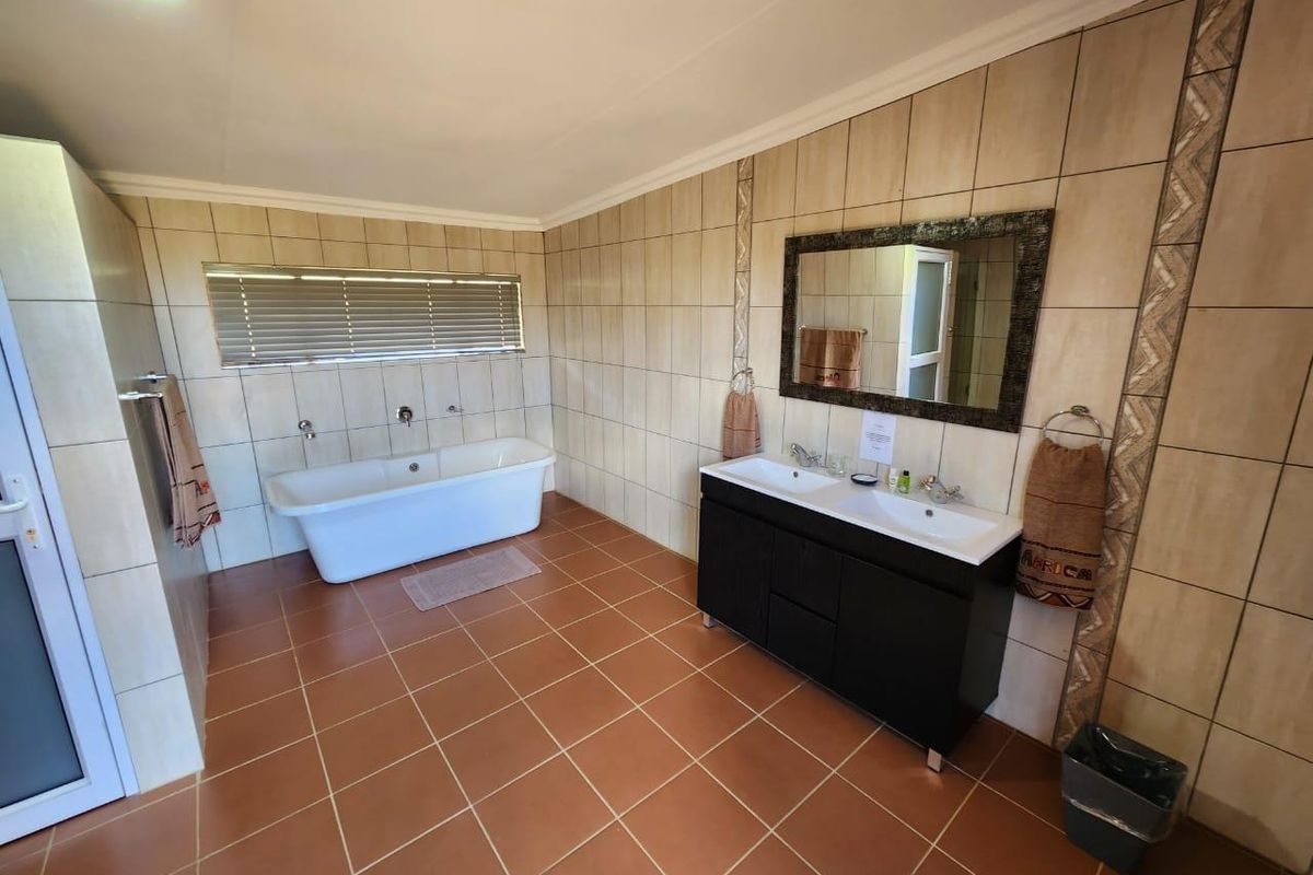 Spacious bathroom featuring a freestanding bathtub, double vanity with integrated sinks, and full-height wall tiling.