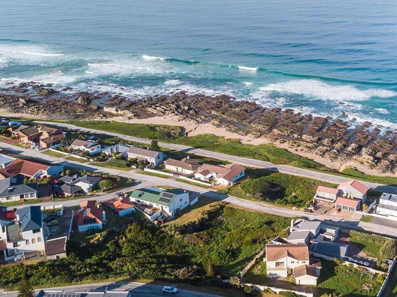 An aerial view of a coastal residential neighborhood showing proximity to the ocean, rocky shoreline, and local road infrastructure.