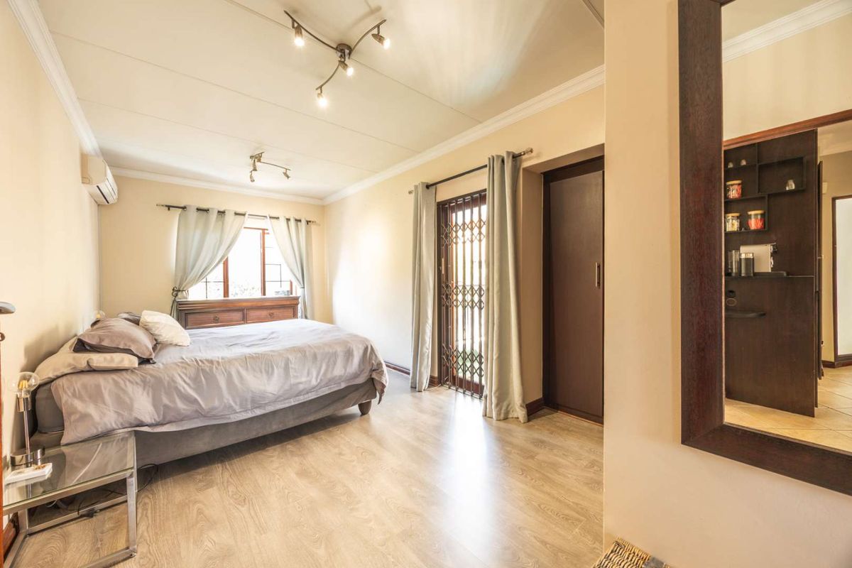 Spacious bedroom featuring laminate flooring, built-in cupboards, air conditioning, and direct access to an outdoor area through a secure gate.