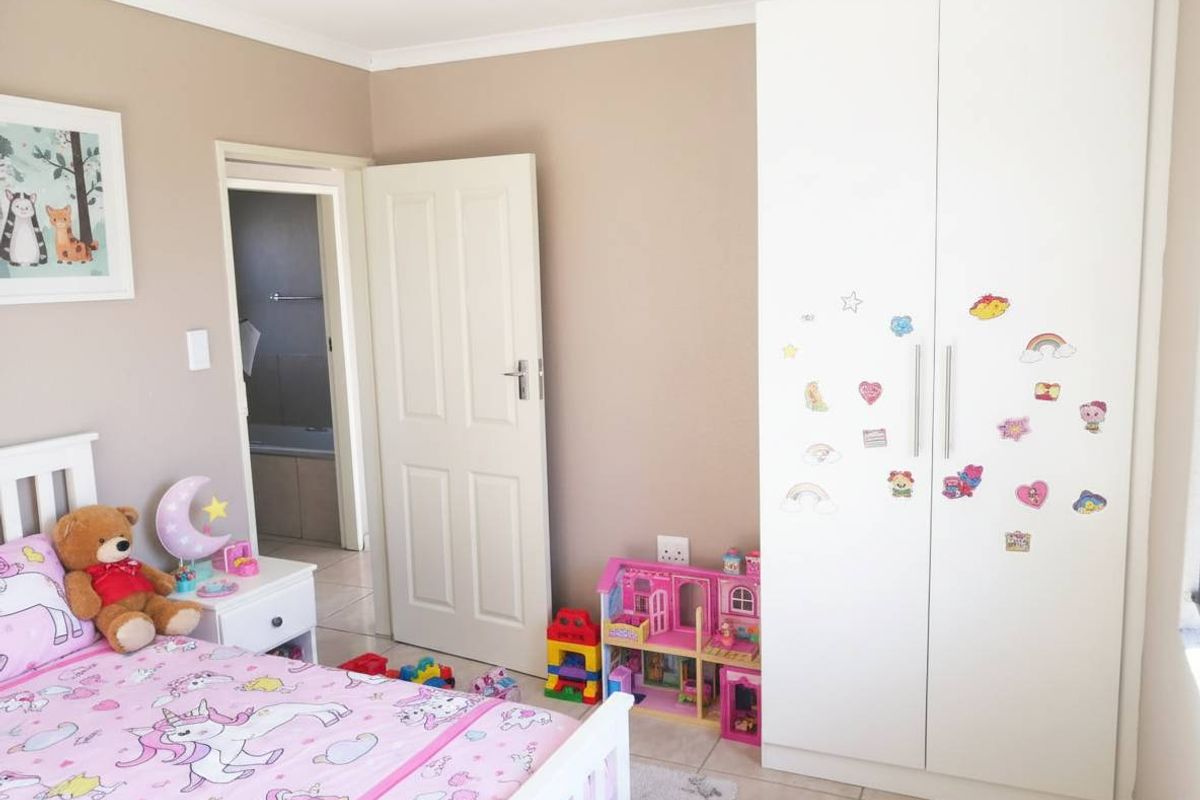 A bedroom featuring built-in white cabinetry and tiled flooring, with an adjacent bathroom visible through the doorway.