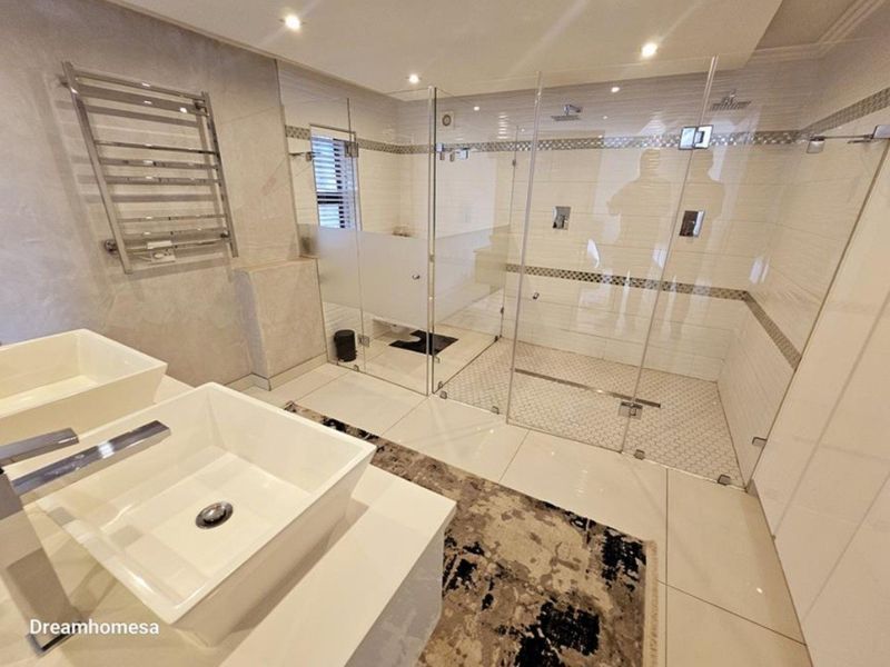 Modern luxury bathroom featuring a spacious walk-in glass shower, double vanity with vessel sinks, and a heated towel rail.