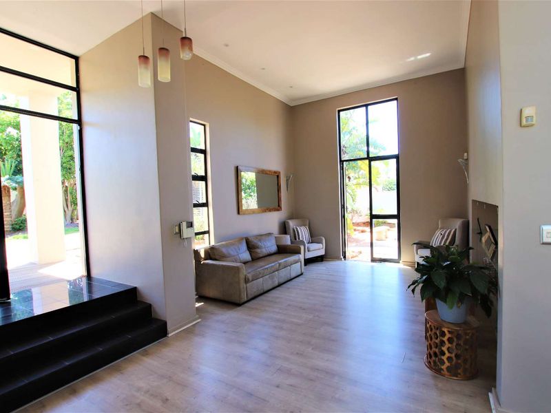 Spacious living room featuring high ceilings, laminate flooring, a built-in fireplace, and large black-framed glass doors providing access to the outdoor area.