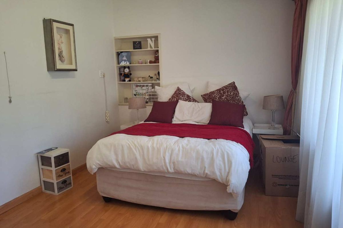 A bedroom featuring laminate flooring and a built-in wall shelving unit.