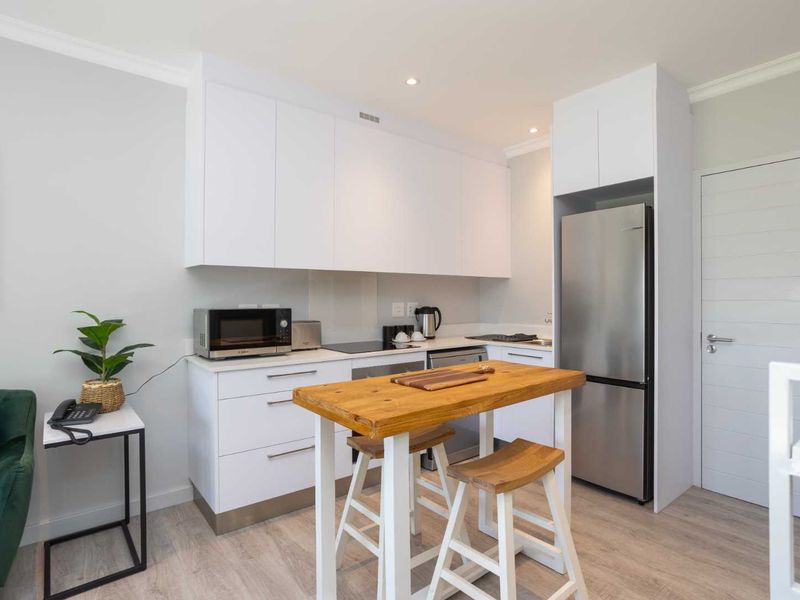 Modern kitchen featuring white cabinetry, stainless steel appliances, and light wood-look flooring, providing a clean and functional cooking space.