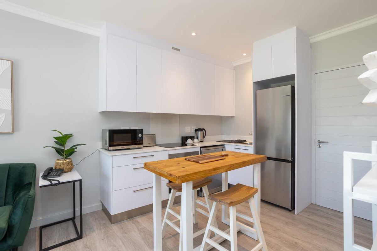 Modern kitchen featuring white cabinetry, stainless steel appliances, and light wood-look flooring, providing a clean and functional cooking space.