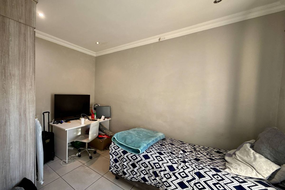 A functional bedroom featuring tiled flooring, recessed downlighting, crown molding, and a built-in wardrobe.