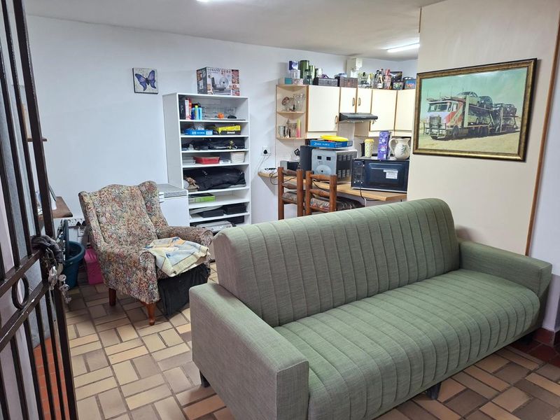Open plan living area featuring tiled flooring and a compact kitchen corner with built-in cabinetry and an extractor fan.