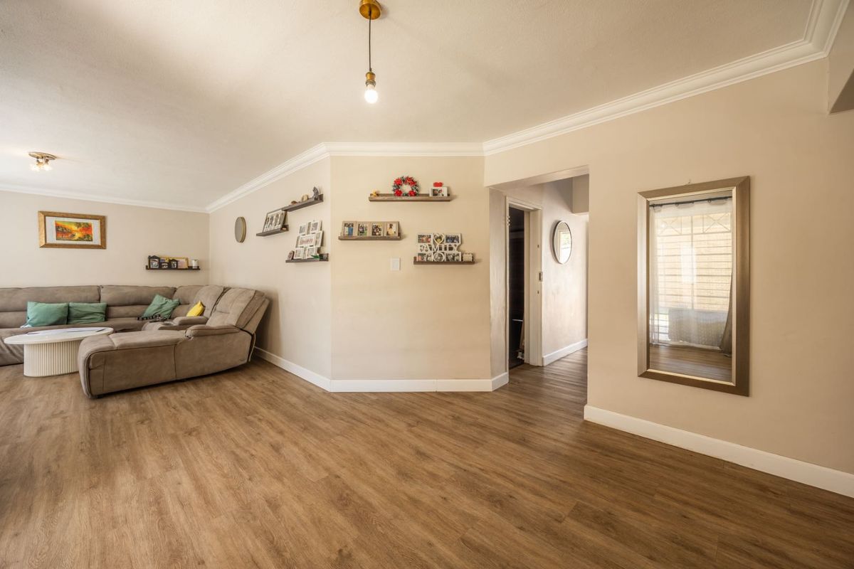 Spacious living room featuring modern laminate flooring, neutral wall tones, and decorative cove cornicing, creating a bright and inviting atmosphere.