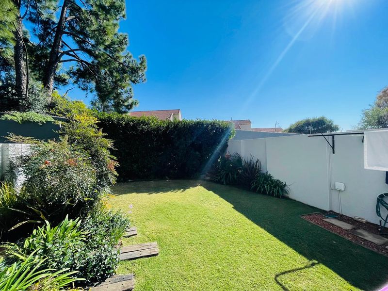 A well-maintained private garden featuring a neat lawn, established perimeter hedging, and boundary walls, providing a pleasant outdoor space.