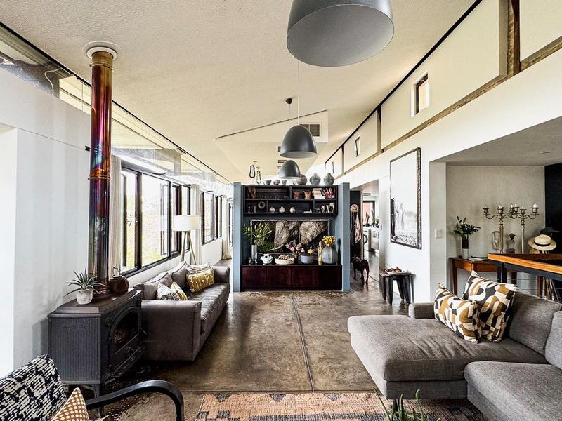 Spacious living area featuring polished concrete floors, a striking freestanding wood-burning fireplace, and high clerestory windows that provide abundant natural light.