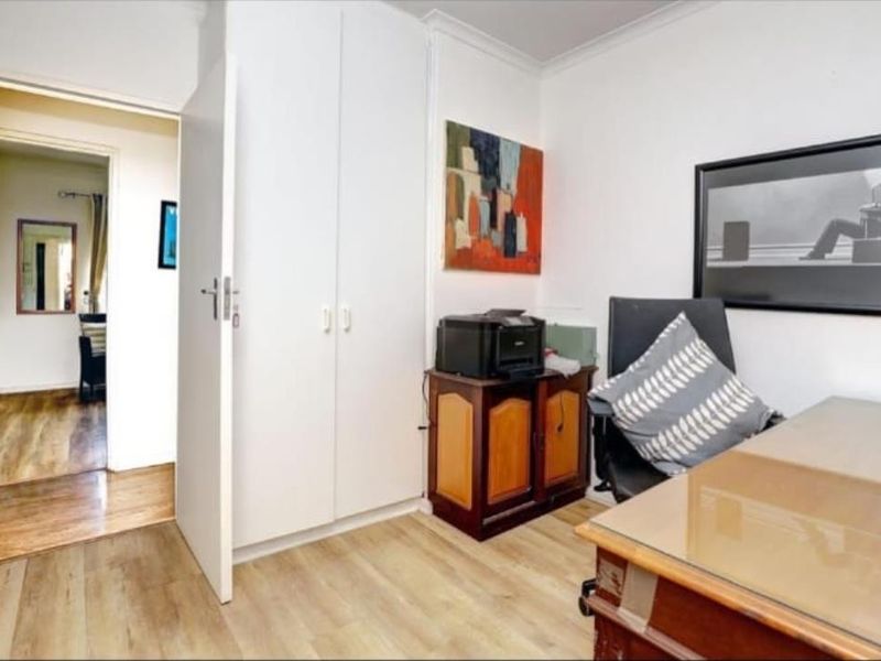 A functional home office space featuring light-toned laminate flooring and built-in storage cupboards, providing a practical area for work or study.