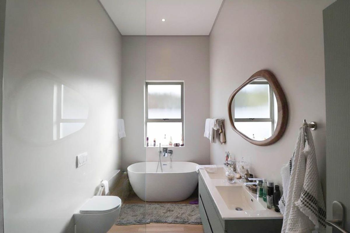 Modern bathroom featuring a freestanding bathtub, wall-mounted toilet, and a double vanity with integrated sinks.