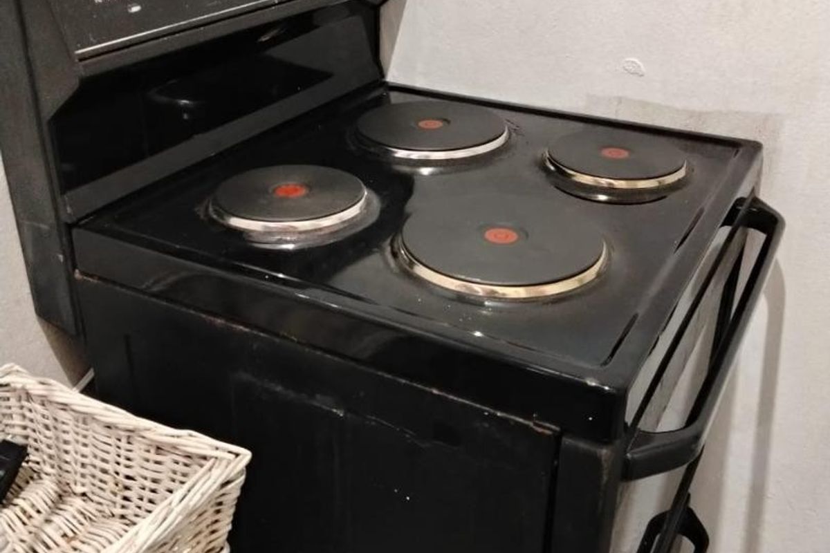 A close-up view of a black freestanding electric stove with four solid plates, situated in a kitchen area.