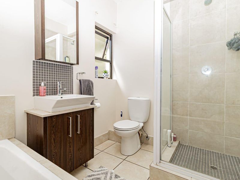 A well-maintained bathroom featuring a vanity with basin, a separate shower enclosure with tiled walls, a toilet, and a bathtub.