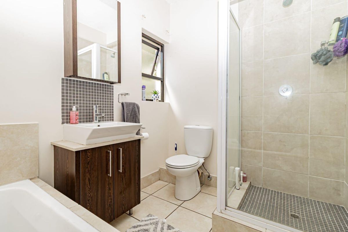 A well-maintained bathroom featuring a vanity with basin, a separate shower enclosure with tiled walls, a toilet, and a bathtub.