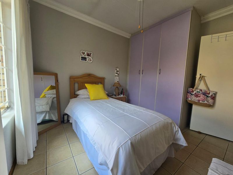 A bedroom featuring tiled flooring, built-in cupboards, and decorative ceiling cornicing.