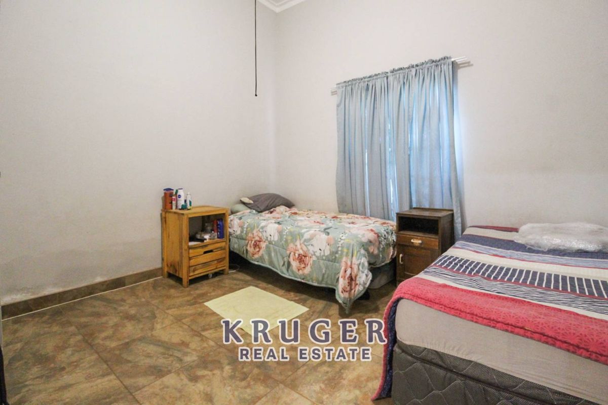 A functional bedroom featuring tiled flooring and a window with curtain tracks.