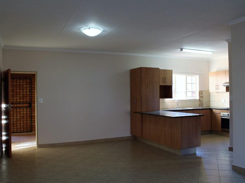 Open plan living area featuring a functional kitchen with built-in cabinetry, oven, extractor fan, and tiled flooring throughout.
