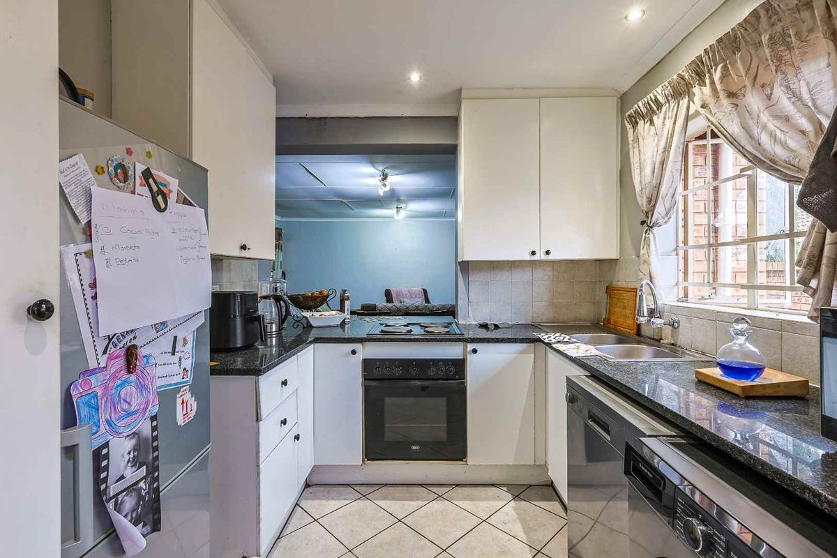 Functional kitchen featuring granite countertops, built-in oven, hob, and double sink, with an open-plan layout connecting to the adjacent living area.